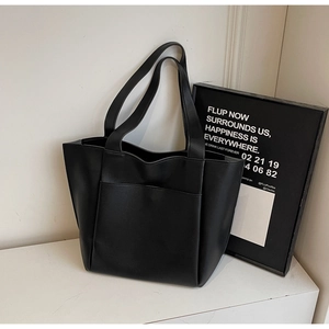 Detail view of a black large tote bag with functional front pocket and smooth leather texture