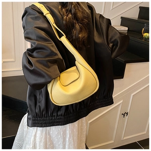 Detailed view of bright yellow crescent bag in lychee pattern leather worn by a model