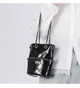 Detailed view of black quilted leather bucket bag with silver chain and metal lock
