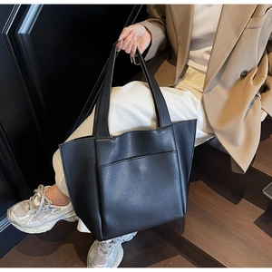 Close-up of black lychee grain leather tote bag worn by a model in a commuter style