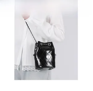 Detail of quilted drawstring bucket bag with silver chain trim and shiny leather texture