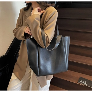 Detail of black pebbled leather tote bag with front pocket worn with office attire