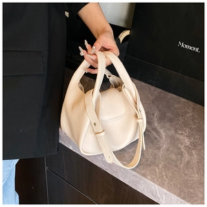 Detailed view of cream pebble leather texture and fine stitching on the stylish bucket bag