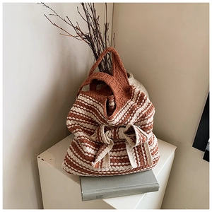 Dettaglio della trama intrecciata di una grande borsa tote con design a fiocco a righe