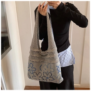 Detail of grey-blue knit tote bag featuring floral patterns and hollow mesh texture