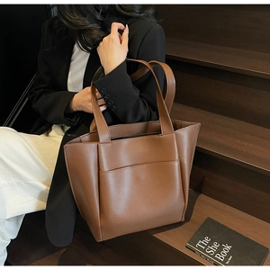 Detailed view of a brown lychee pattern tote bag with front pocket shown on stairs