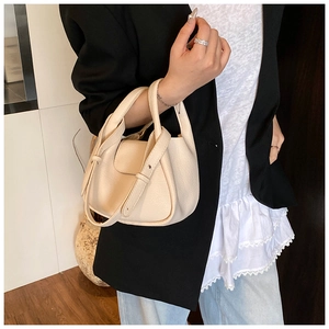 Detail of a creamy white lychee textured mini handbag with unique knotted handle design