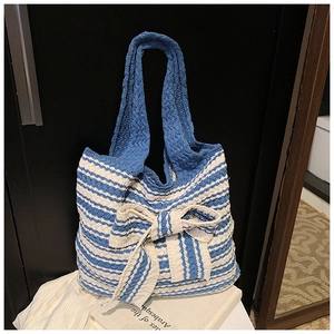 Dettaglio della borsa tote in maglia a righe blu e bianche con grande fiocco