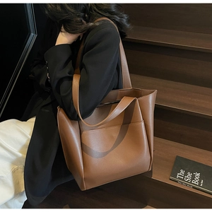 Close-up of brown leather tote bag with external pocket and fine pebble grain texture