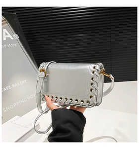 Detailed view of silver metallic leather shoulder bag with woven eyelet texture