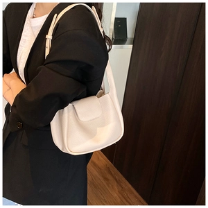 Detail of cream leather shoulder bag showing lychee grain texture and metal buckle