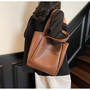 Close-up of a large brown faux leather tote bag with front pocket for daily commute