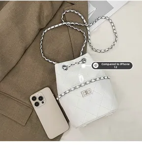 Mini white bucket bag in quilted leather shown next to iPhone 12 for size comparison