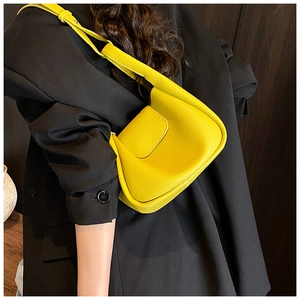 Detail of yellow pebbled leather shoulder bag showing the texture and crossbody strap