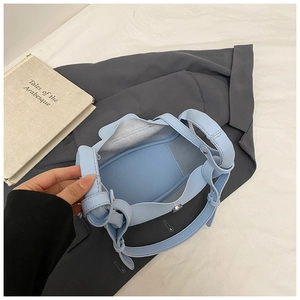 Detail shot of light blue bucket bag showing inner space, magnetic clasp, and litchi texture