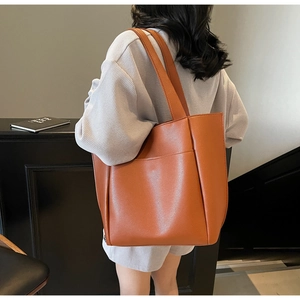 Rear view of a caramel brown large tote bag with front pocket shown on a model