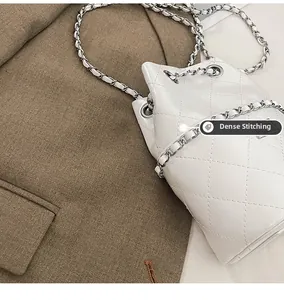 Close-up of precise stitching and quilted texture on a white leather bucket bag