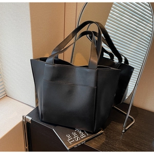 Macro detail of black pebble leather tote bag featuring a practical front patch pocket