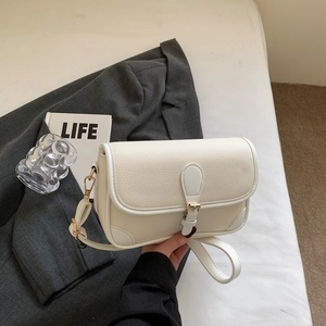 Cream off-white leather shoulder bag with gold buckle on a stylish blazer background