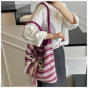 Dettaglio della borsa tote in maglia a righe viola e bianche con grande fiocco laterale