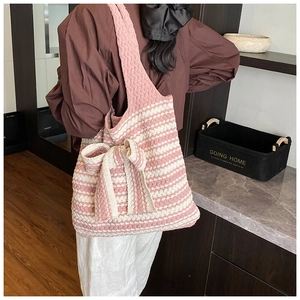 Borsa tote in maglia a righe rosa con fiocco grande indossata sulla spalla