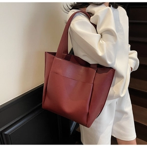 Deep burgundy tote bag with litchi grain texture carried by a model on a shoulder
