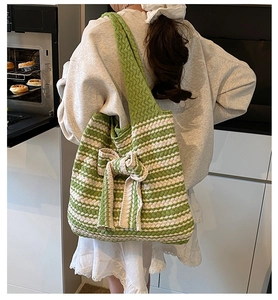 Borsa tote in maglia a righe verdi e bianche con grande fiocco mostrata su modella