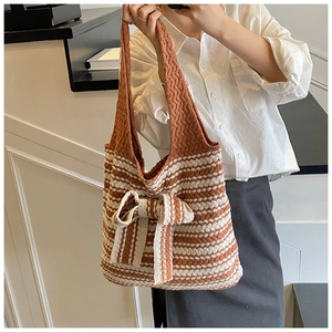 Dettaglio borsa tote in maglia a strisce marroni con un grande fiocco decorativo