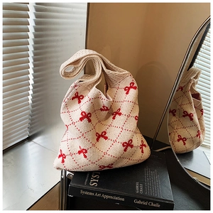 Close-up of knit tote bag with red bows and diamond pattern in soft shadows