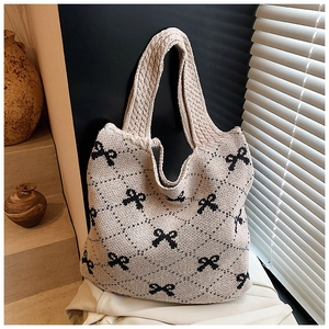 Detailed knit tote bag with black bow pattern and soft diamond texture on a stone step