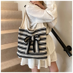 Dettaglio della borsa tote in maglia a righe a contrasto con un grande fiocco
