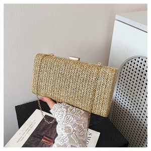 Primo piano della pochette intrecciata dorata con tracolla a catena tenuta in mano