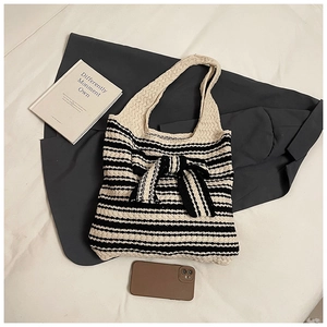 Dettaglio della borsa tote in maglia con strisce bianche e nere e un grande fiocco decorativo