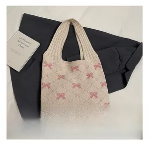 Detail of knitted tote bag showing pink bow patterns and rhombus textured weave on beige fabric