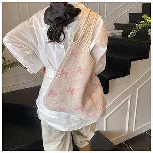 Detailed view of cream knitted tote bag with pink bow pattern on a model's shoulder
