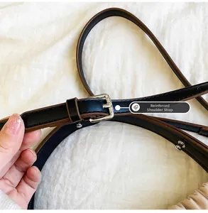 Détail de la bandoulière en cuir noir renforcé avec boucle argentée et rivets métal