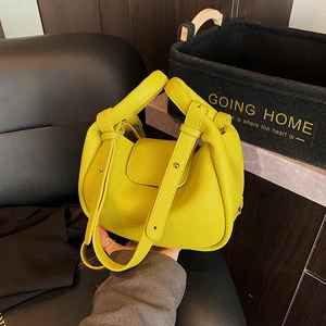 Large bright yellow pebbled leather tote bag with flap closure and decorative metal studs