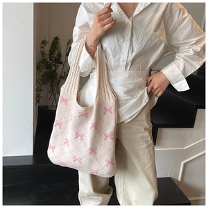 Chic knit tote bag with pink bow pattern shown on model in a minimalist setting