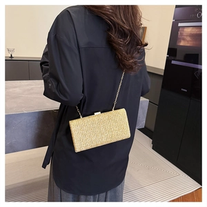 Dettaglio della pochette in paglia oro champagne con trama intrecciata e catena dorata