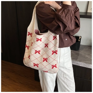 Detailed view of knitted tote bag featuring red bow patterns and soft fabric texture