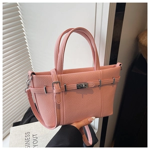 Detail of pink lychee leather handbag with silver twist lock and natural light shadows