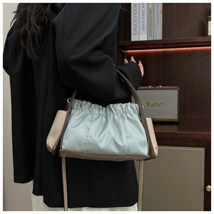 Detail einer hellblauen Plissee-Schultertasche mit Kontrastbesatz an einem Model getragen