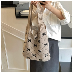 Detail of beige knitted tote bag featuring black bow patterns and diamond weave texture