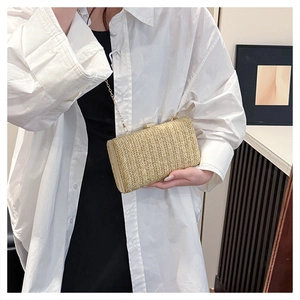 Dettaglio della trama in paglia a V di una borsa pochette dorata con catena sottile