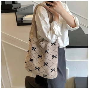 Detailed knit texture of beige oversized tote bag with black bow jacquard pattern