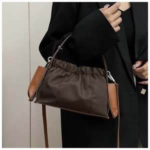 Detail einer gefalteten dunkelbraunen Nylonhandtasche mit Lederseiten und Metallhaken