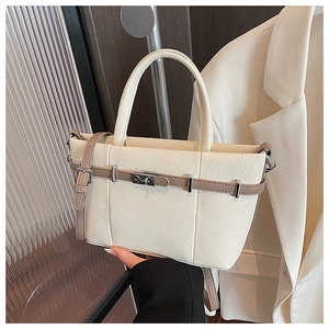 Detail of minimalist beige pebble leather tote bag with brown straps and silver metal buckle