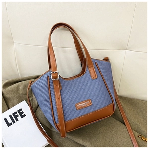 Détail du sac cabas tissé bleu avec bordure en cuir marron et lettrage de mode