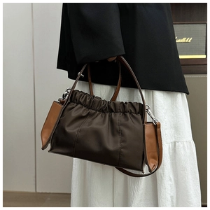 Détail du sac bandoulière plissé bicolore en tissu marron avec accents en cuir