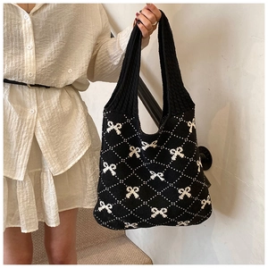 Detail of the knit texture and white bow pattern on the large casual black shoulder bag